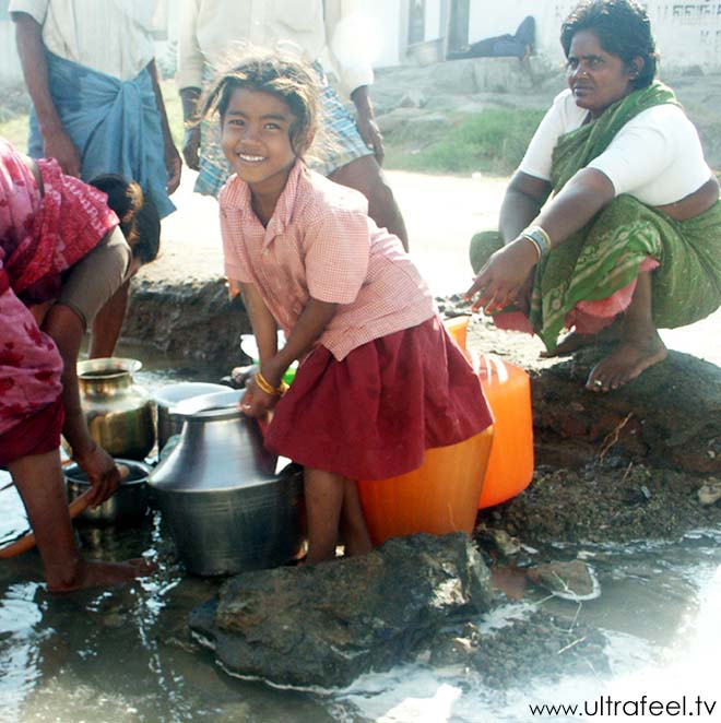 Indian people with steel sheet jugs collecting dirty water to drink! Seen in Tiruvannamalai, Tamil Nadu, India.